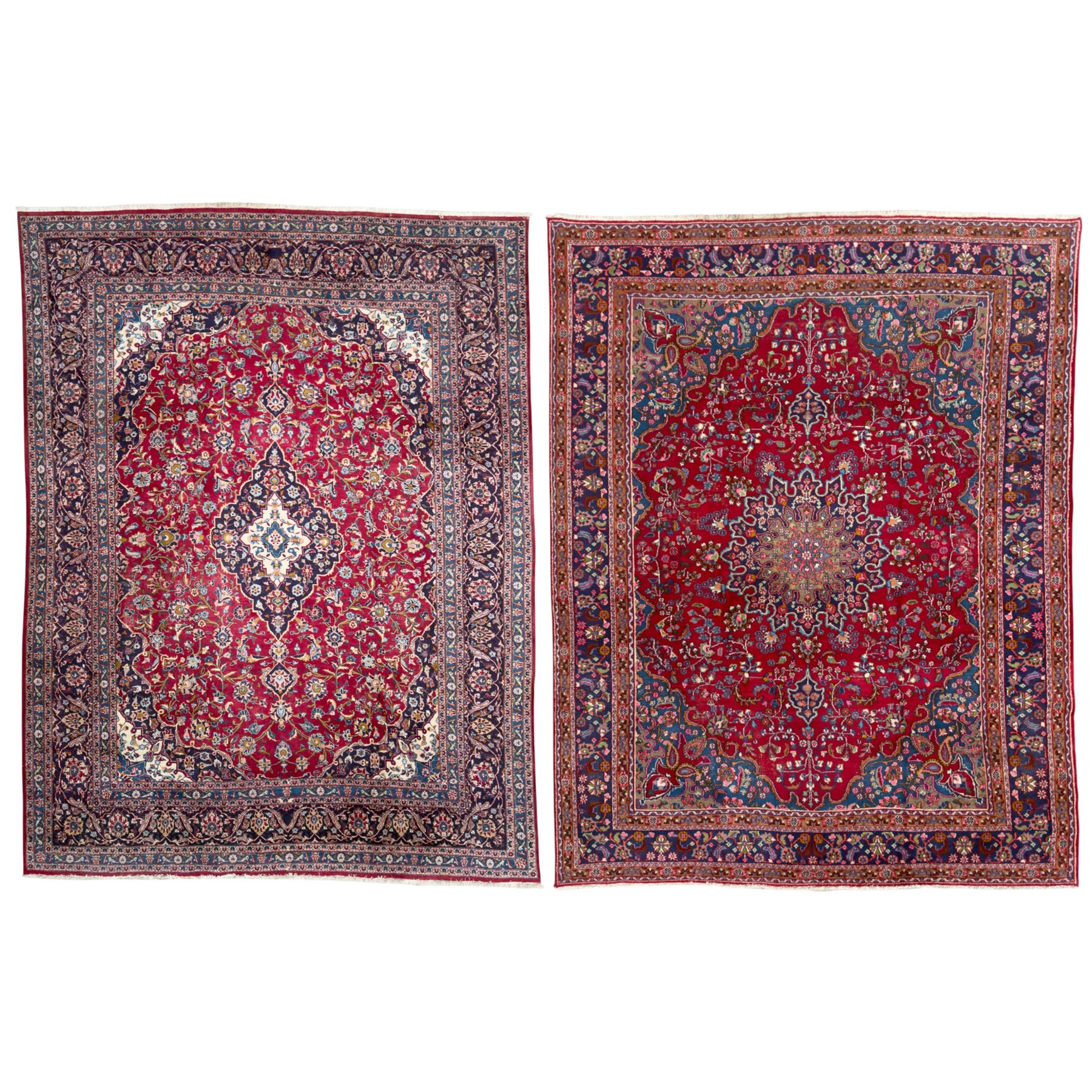 Pair of Persian wool rugs, each with rich red ground, one centred with a diamond-shaped medallion and navy spandrels within a floral field, the other with radiating floral medallion and scrolling foliate motifs, both enclosed by multiple borders with palmette and flowerhead designs, from the region of Kashan 291x376, 299 x 378 