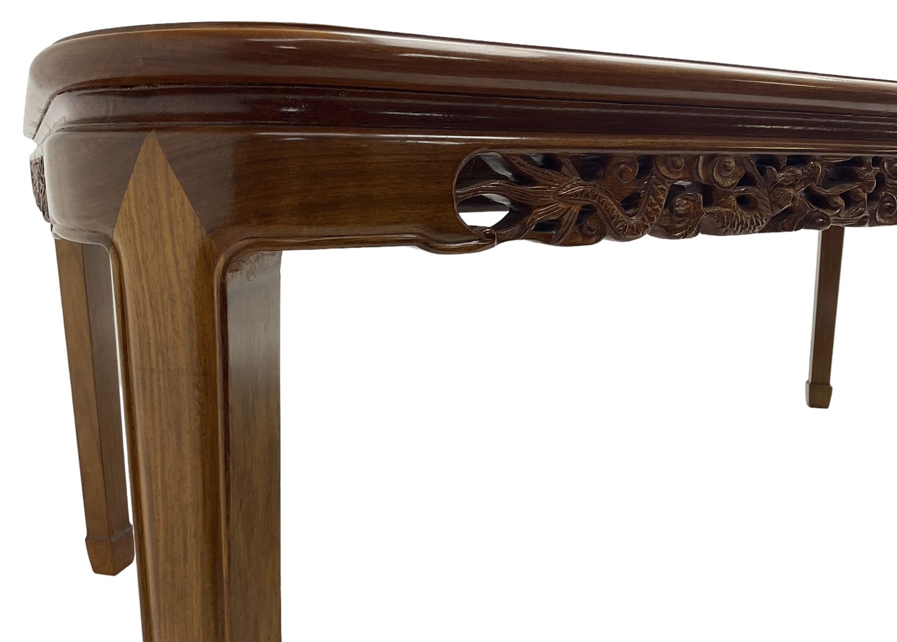 Late 20th century Chinese carved hardwood extending dining table, rectangular panelled top with rounded corners over a pierced frieze carved with dragon motifs and scrolling foliate decoration, with two additional leaves
