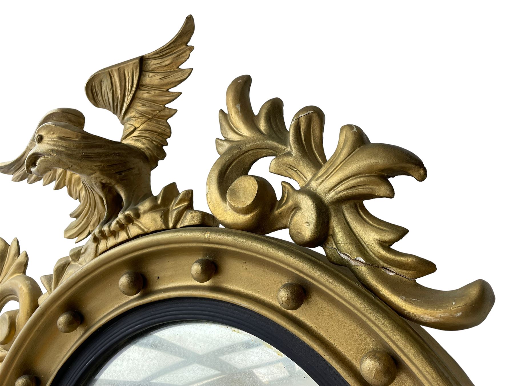 Pair of Regency period giltwood convex wall mirrors, moulded circular frame decorated with spherical mounts surmounted by a carved eagle with spread wings, foliage scroll carved upper and lower brackets, reed moulded and ebonised slip enclosed convex mirror plate 