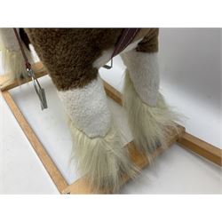 Modern plush covered rocking horse with inset eyes, simulated leather bridle and saddle with metal stirrups, on curving wooden rockers L94cm H64cm