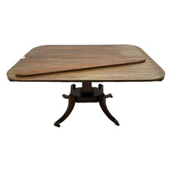 Regency mahogany dining table, rectangular top with rounded corners and reeded edge, raised on square pedestal with platform, terminating to sabre supports with brass cups and castors