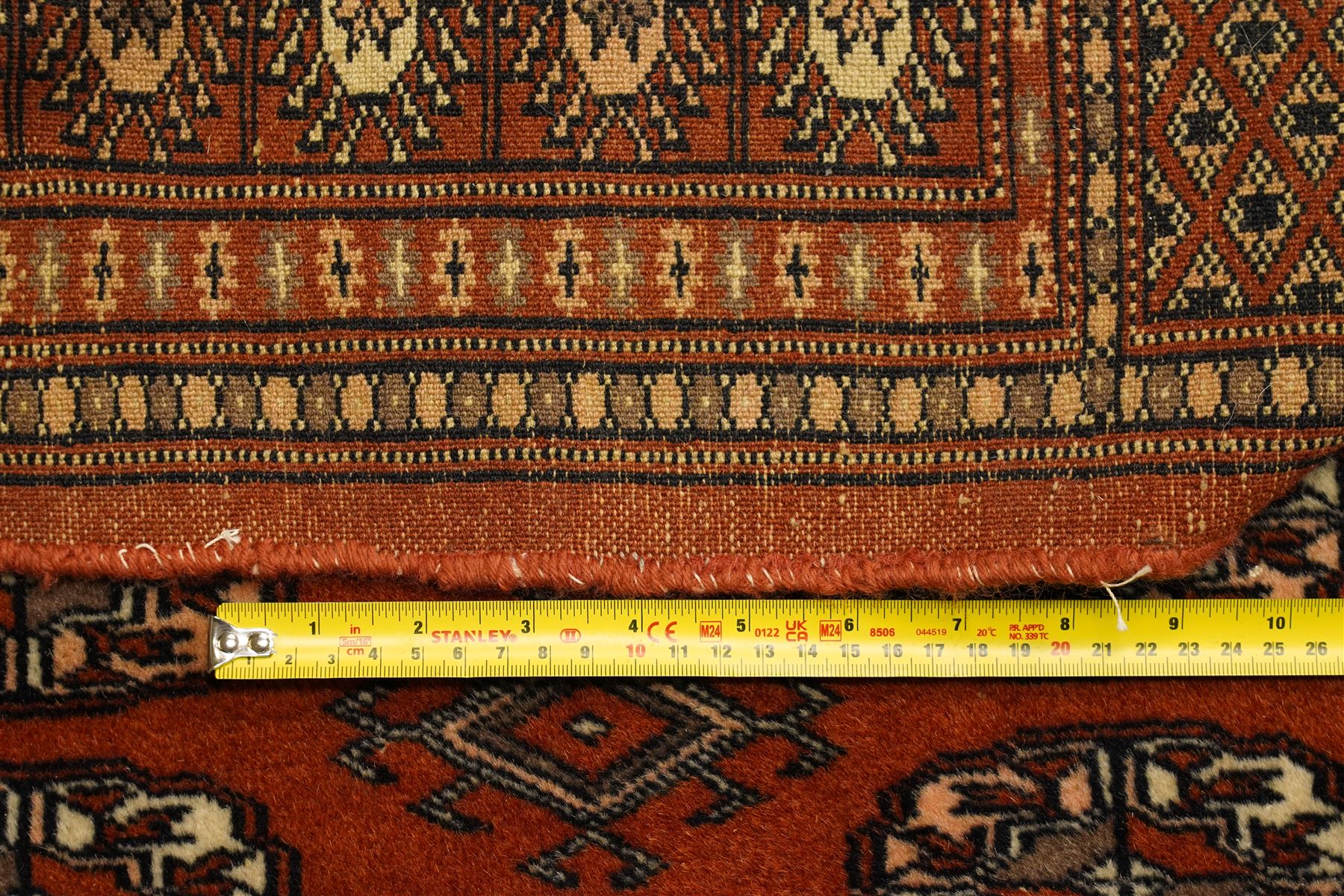 Bokhara hand-knotted carpet, terracotta ground with repeating rows of Tekke guls interspersed with geometric motifs, enclosed by multiple stylised floral and geometric borders, with fringed ends