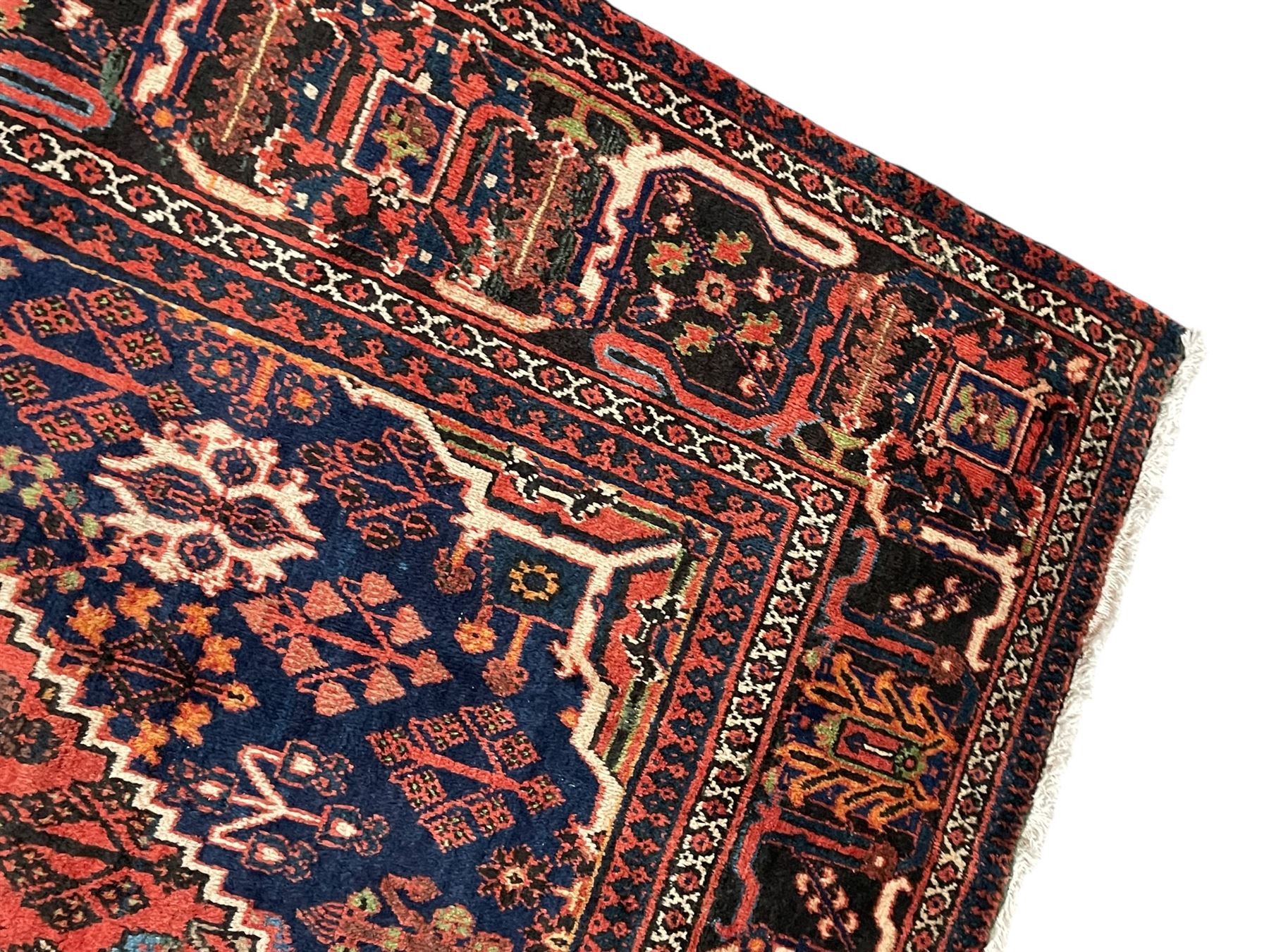 Persian Joshgan red ground rug, the medallion, field and spandrels decorated with clusters of Pitrak and tree of life motifs, the border with repeating design decorated with stylised plant motifs, within guard stripes