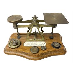 Brass postage scales on shaped moulded mahogany base, bearing ivorine central label 