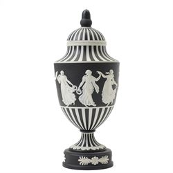 Wedgwood 20th century 'Dancing Hours' jasperware urn, the upper section decorated with a single band of neoclassical maidens in white to a black basalt ground, rising from a circular plinth decorated with foliate motifs, complete with cover with acorn finial, stamped 'Wedgwood Made in England', H25cm 