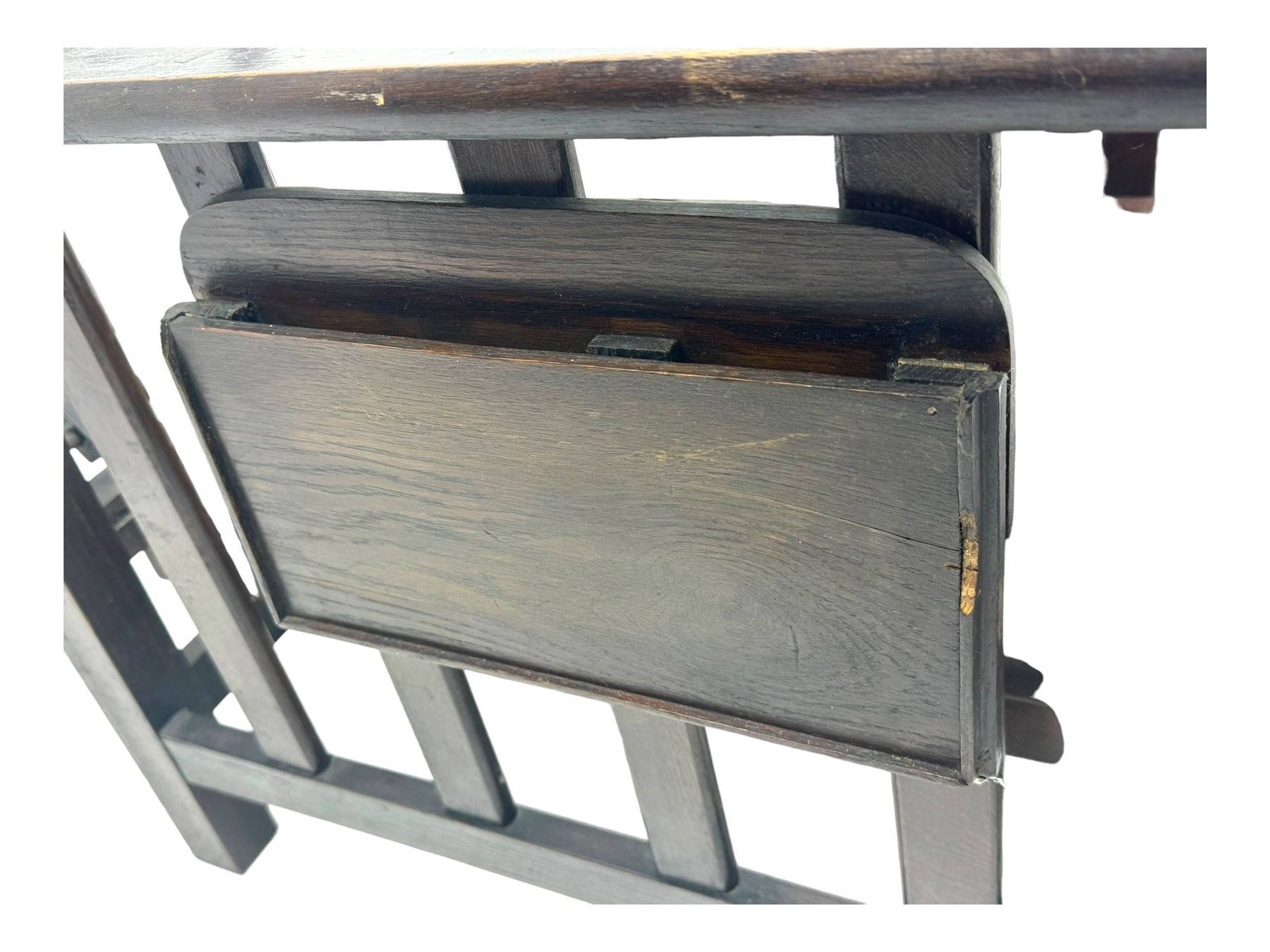 Late Victorian oak steamer chair, adjustable slatted backrest with grooved crest rail, wide armrests extending to a sliding adjustable footrest, open frame sides with vertical slats, side magazine rack and collapsible table, raised on turned front supports