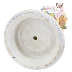 Late 19th/early 20th century Continental bisque figures, the larger modelled as a pensive female figure sitting upon a well, upon an oval naturalistically modelled base, H39cm, the smaller modelled as a hunts woman holding a bird aloft, with hound by her side, upon a socle base, H35cm