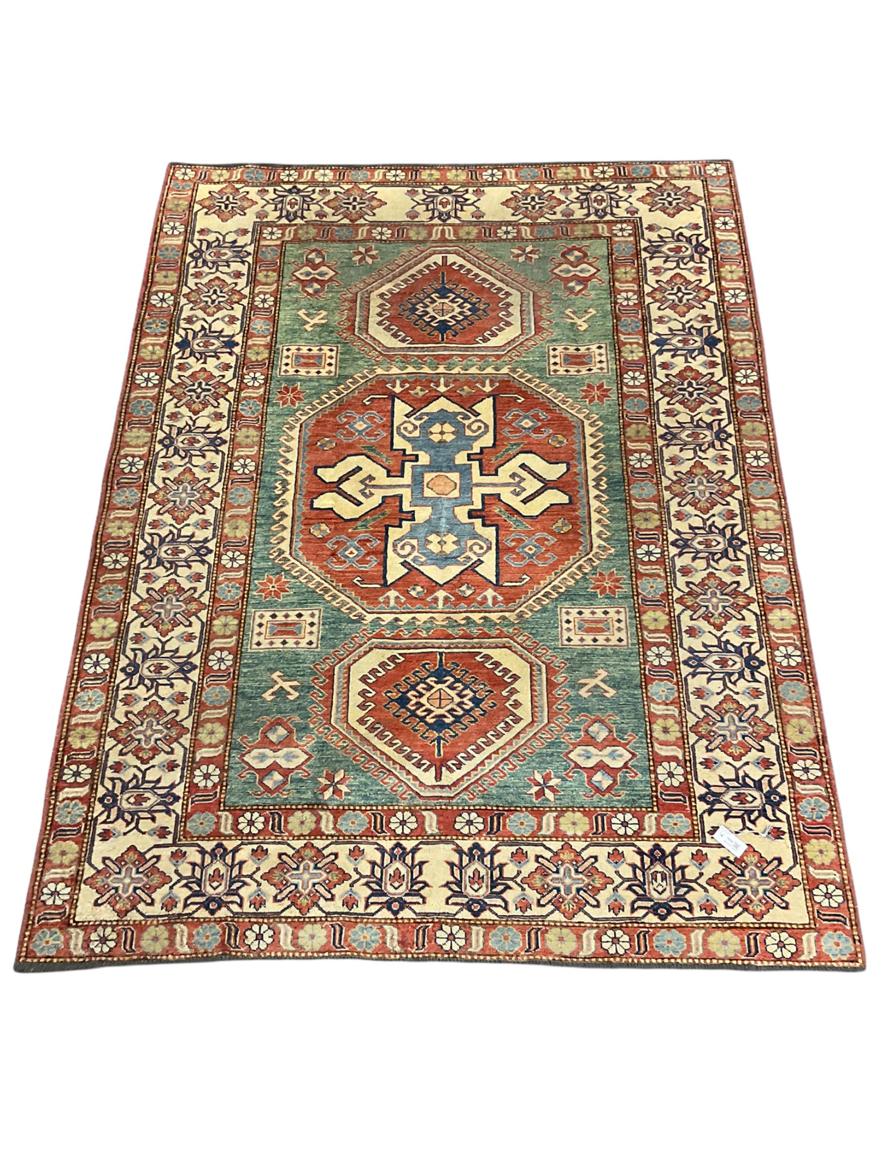Kazakh rug, pale green ground field with three part medallion, three band border decorated with stylised plant motifs