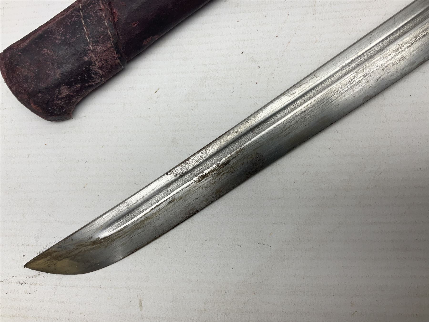 Copy of a WWII Japanese NCO sword, the 65cm slightly curving blade stamped with pseudo Japanese characters and cast brass simulated cord bound grip; in officer's leather bound field scabbard L97cm overall