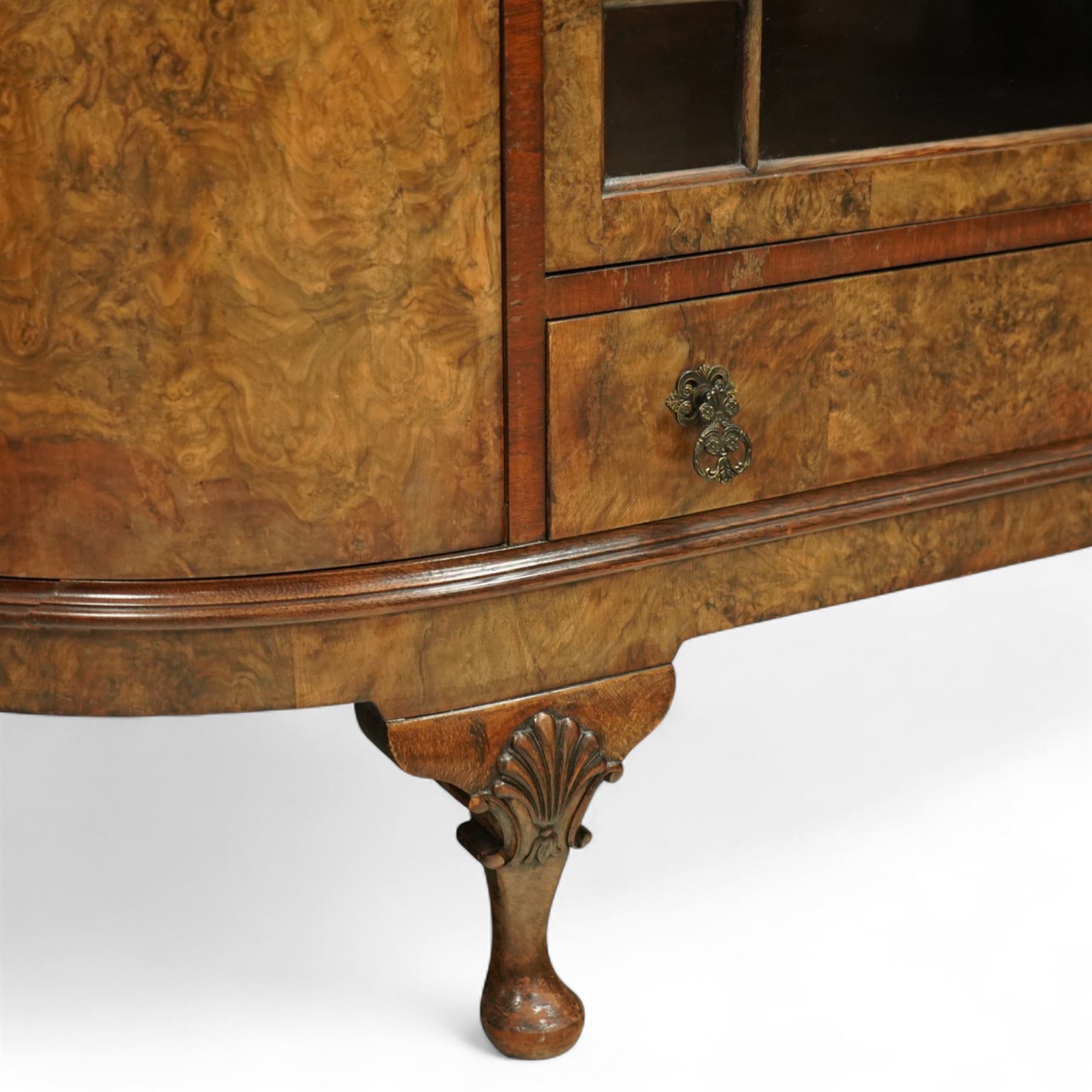 Early 20th century burr walnut display side cabinet, the glass inset top over a central glazed door with geometric astragal glazing, flanked by curved cupboards, shaped apron fitted with drawer, on cabriole legs with shell carved knees and pad feet