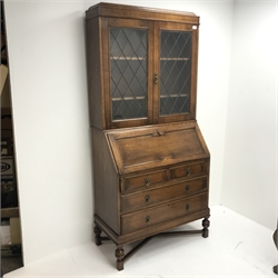 Early 20th century bookcase on bureau, two lead glazed doors above single fall front enclosing fitted interior, two short and two long drawers, cup and cover support joined by stretchers, W95cm, H198cm