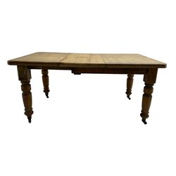 Late Victorian pine extending dining table, rectangular moulded top with canted corners and additional leaf, on turned supports with brass castors 