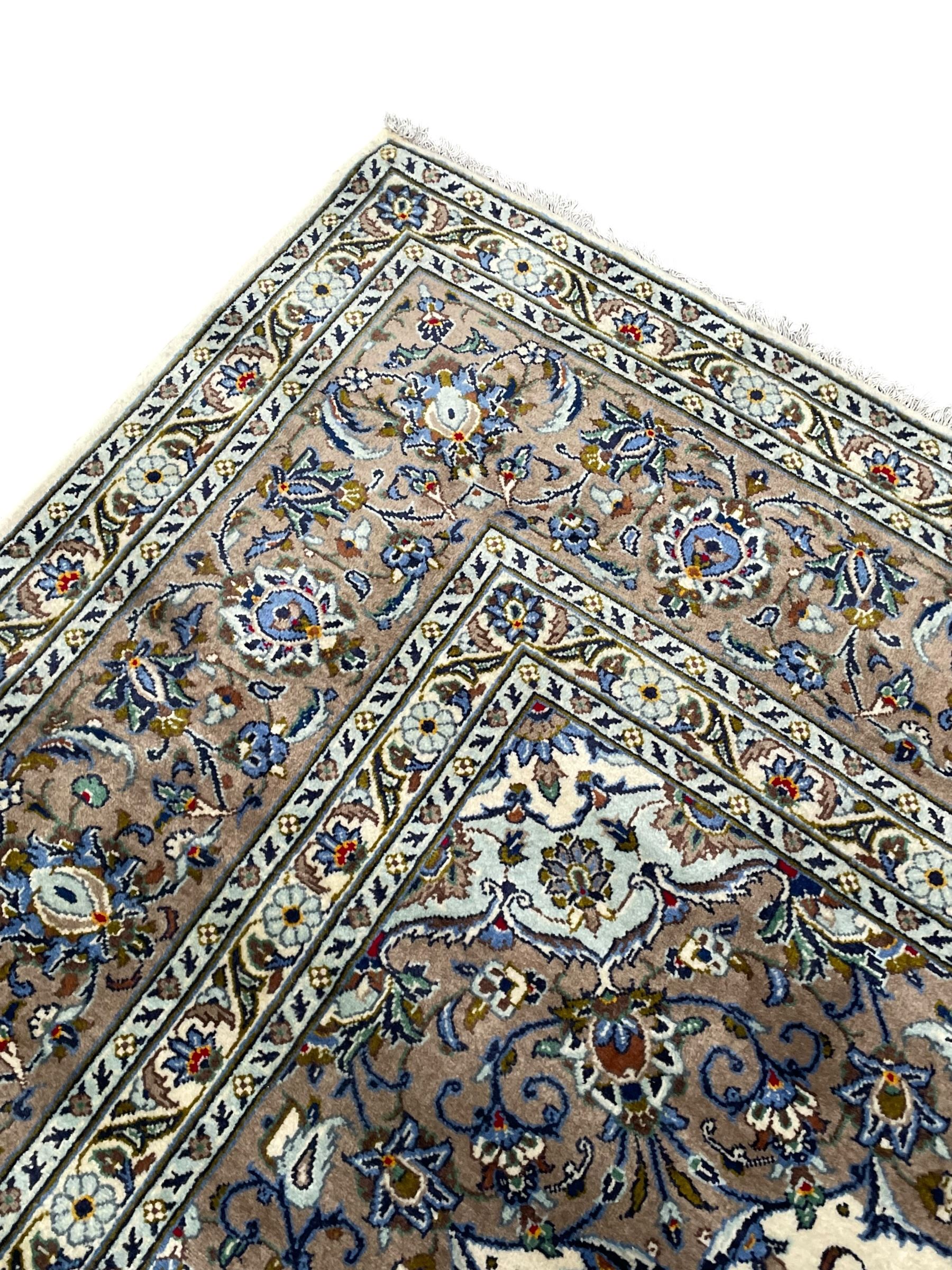 Persian Kashan ivory ground carpet, central medallion on a field of scrolling foliate branches decorated with palmettes, the border decorated with repeating stylised plant motifs, floral design guard stripes