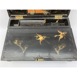  A 20th century Chinese black lacquer and gilt detailed writing box, decorated with figures, pagodas and cranes amidst a mountainous landscape, the hinged cover opening to reveal a compartmented interior and fold out baize lined slope, H20cm L46.5cm D31.5cm.   
