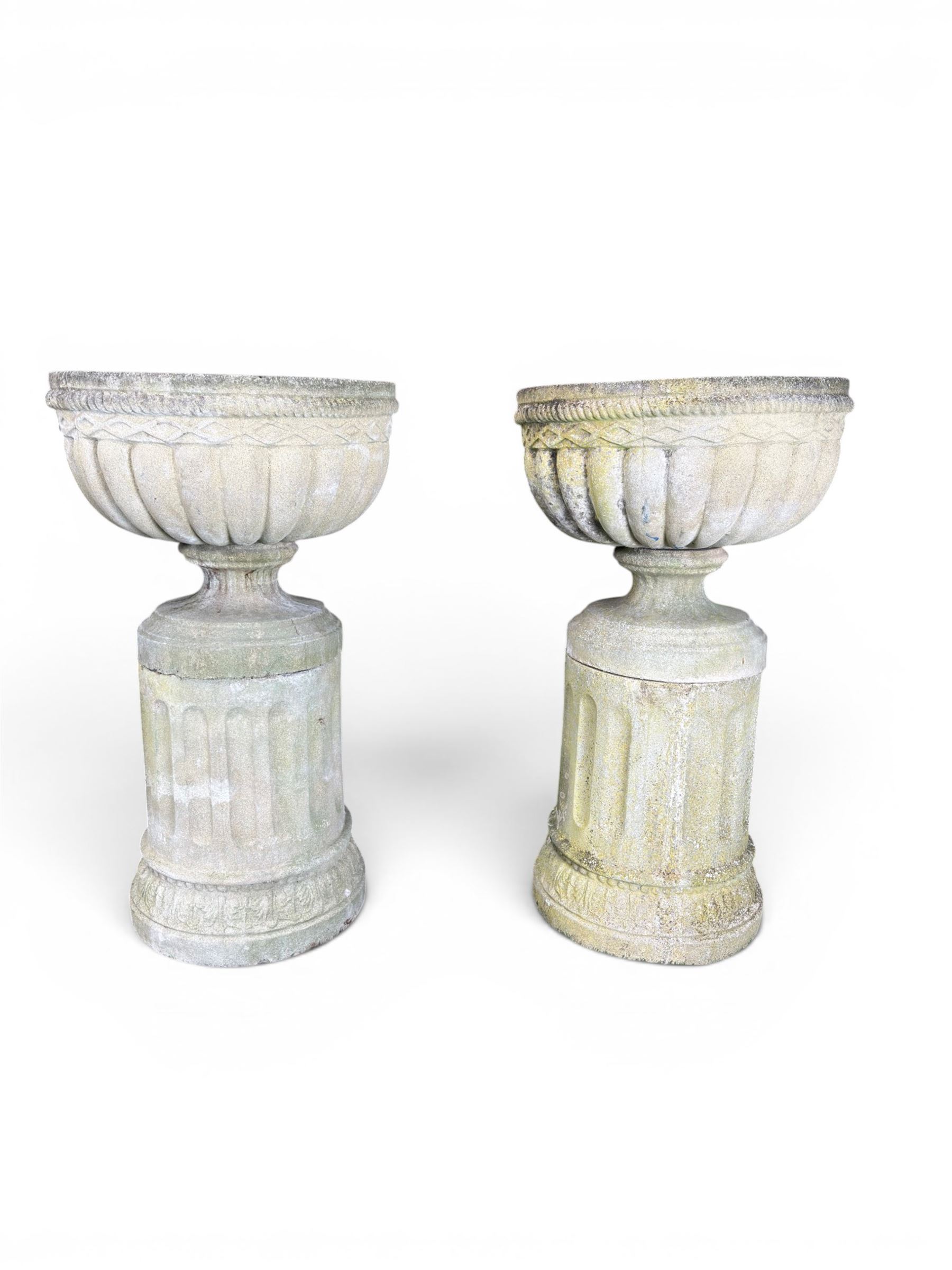 Four 20th century good quality weathered cast stone pedestal urns, circular lobed bowls with rope twist and lattice border, raised on squat base with fluted columns
