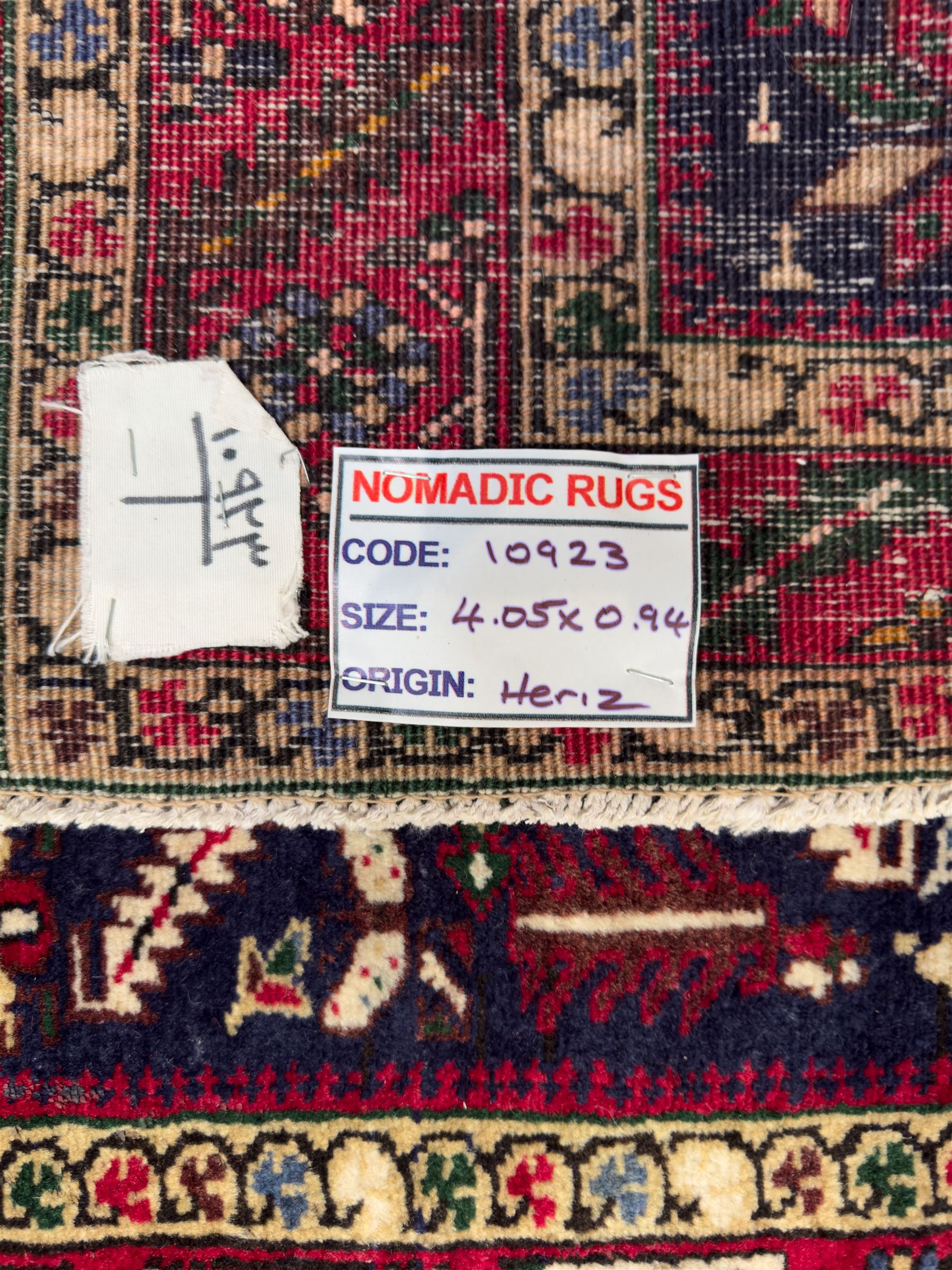 Northwestern Persian Heriz hand-knotted runner, dark indigo field with a series of linked stepped medallions in madder red, ivory, and green, flanked by angular floral motifs, within a madder red border of stylized rosettes and geometric vine motifs 405cm x 95cm