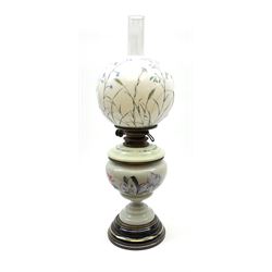 A Victorian oil lamp, with opaque glass reservoir hand painted with flowers beneath a Hinks burner and supporting a globular floral painted opaque glass shade and glass chimney, H47.5cm. 