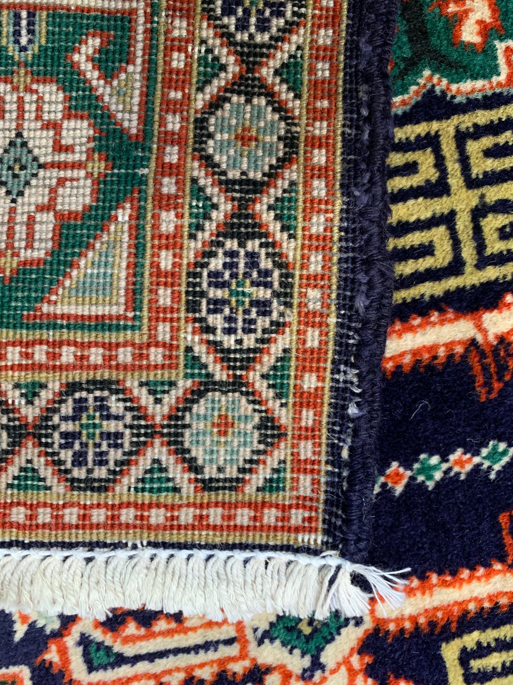 Small Persian indigo ground rug, the field decorated with Gilt motifs with trailing bead and stylised foliage, emerald green ground border decorated with geometric design and flower heads