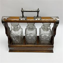 A Mappin & Webb silver plate mounted oak tantalus, containing three square sided cut glass decanters, complete with key, H35cm, together with a further square sided decanter. 