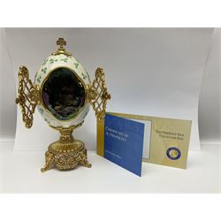 Franklin Mint The Emerald Isle Collector Egg, the egg decorated with embossed shamrocks upon a cream ground, with a gilded shamrock finial, accents and openwork door, opening to reveal a miniature landscape scene, upon three gilded feet set with green paste stones, with certificate of authenticity H23cm, 