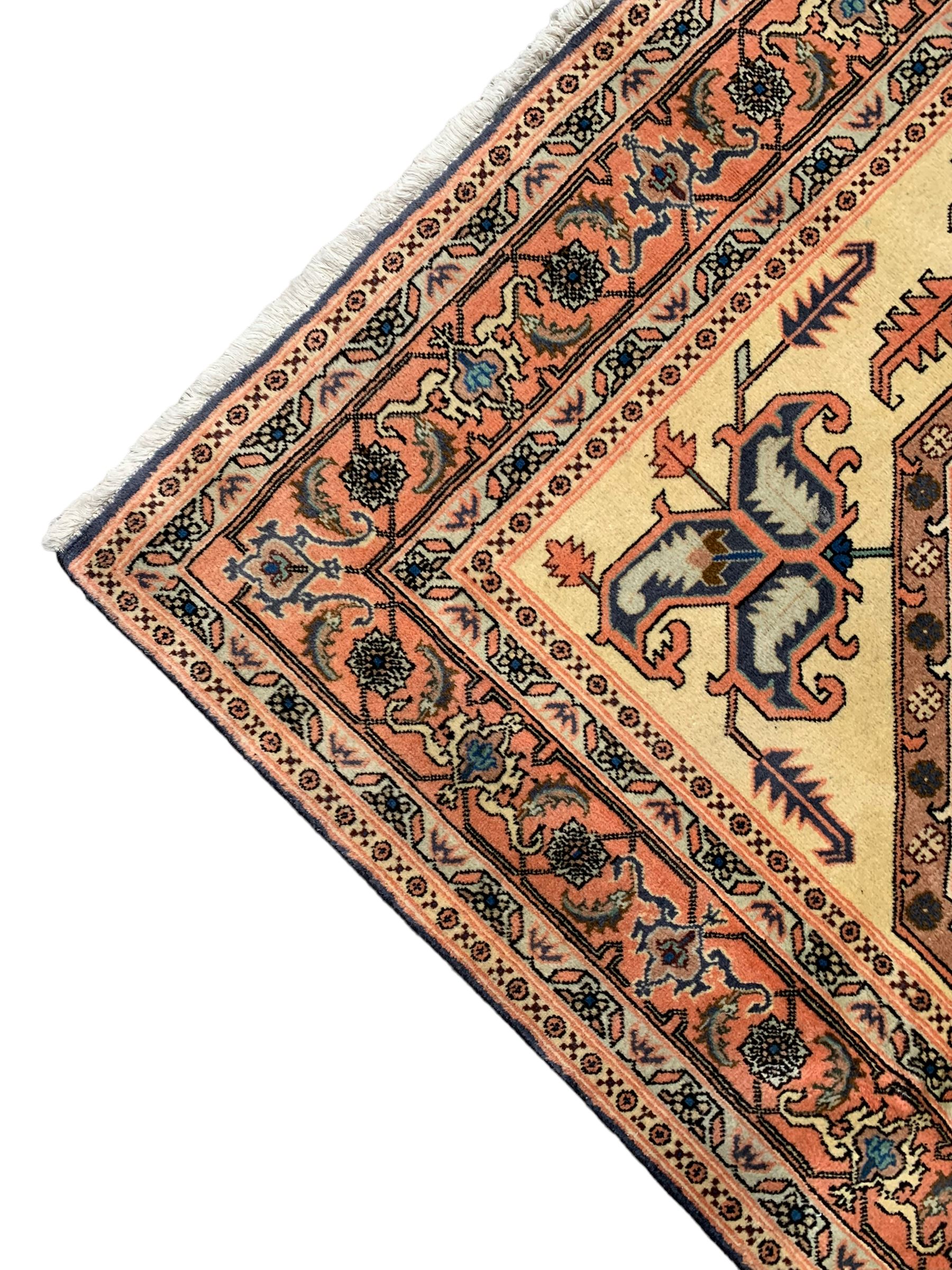 Persian ivory and peach ground, overall geometric design, the field with central star medallion surround stylised leaf motifs, guarded geometric design border