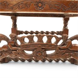 Late Victorian Jacobean Revival oak armchair, the caned back within a pierced and carved foliate frame surmounted by acorn finials, carved scroll arm supports, caned seat, on barley twist supports united by stretchers and carved front rail