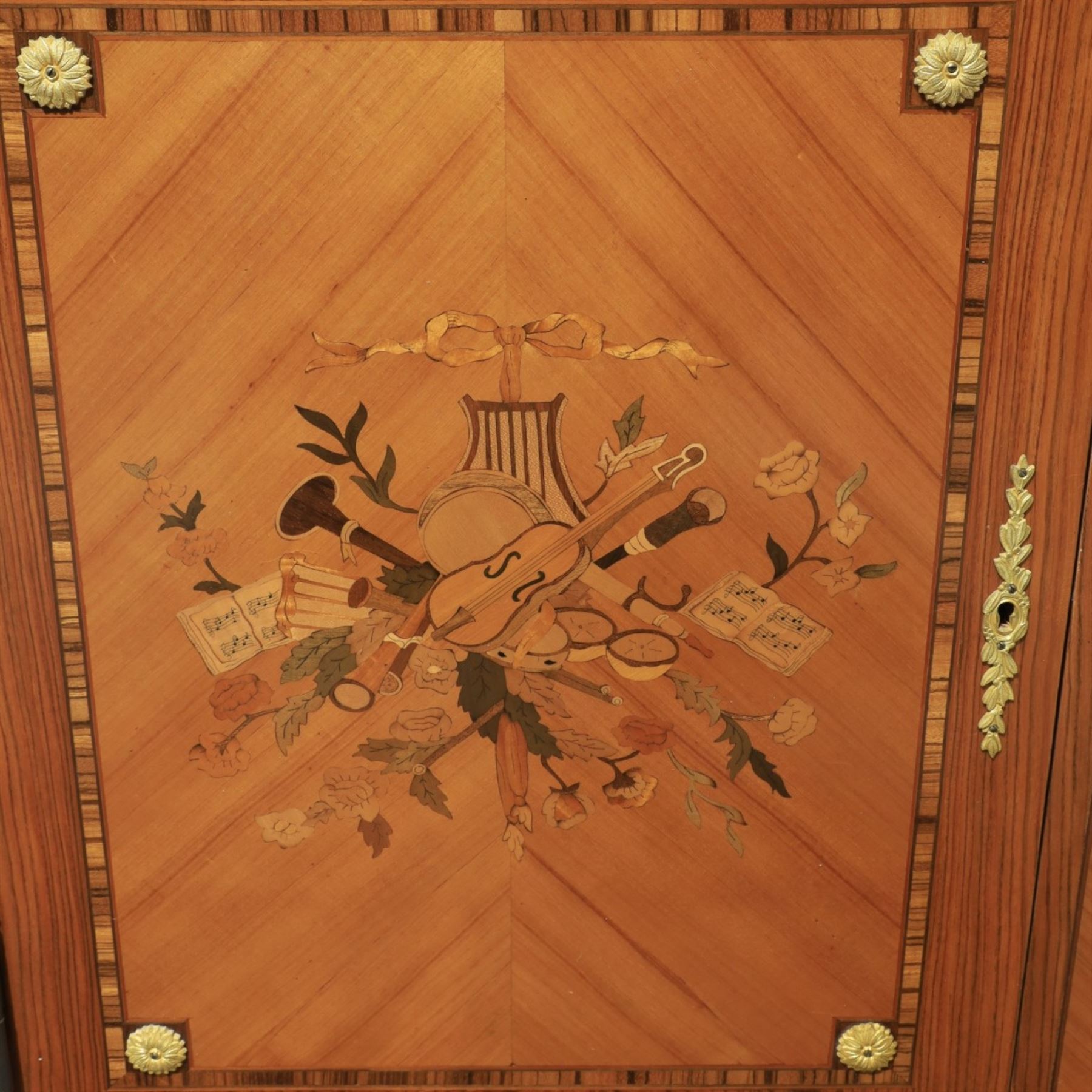French style marquetry display bookcase, with twin glazed upper doors enclosing shelves, over a cupboard base inlaid with musical instruments and foliate decoration, the interior fitted with mirrored cupboard doors and a pull-out shelf, with gilt metal mounts and banding
