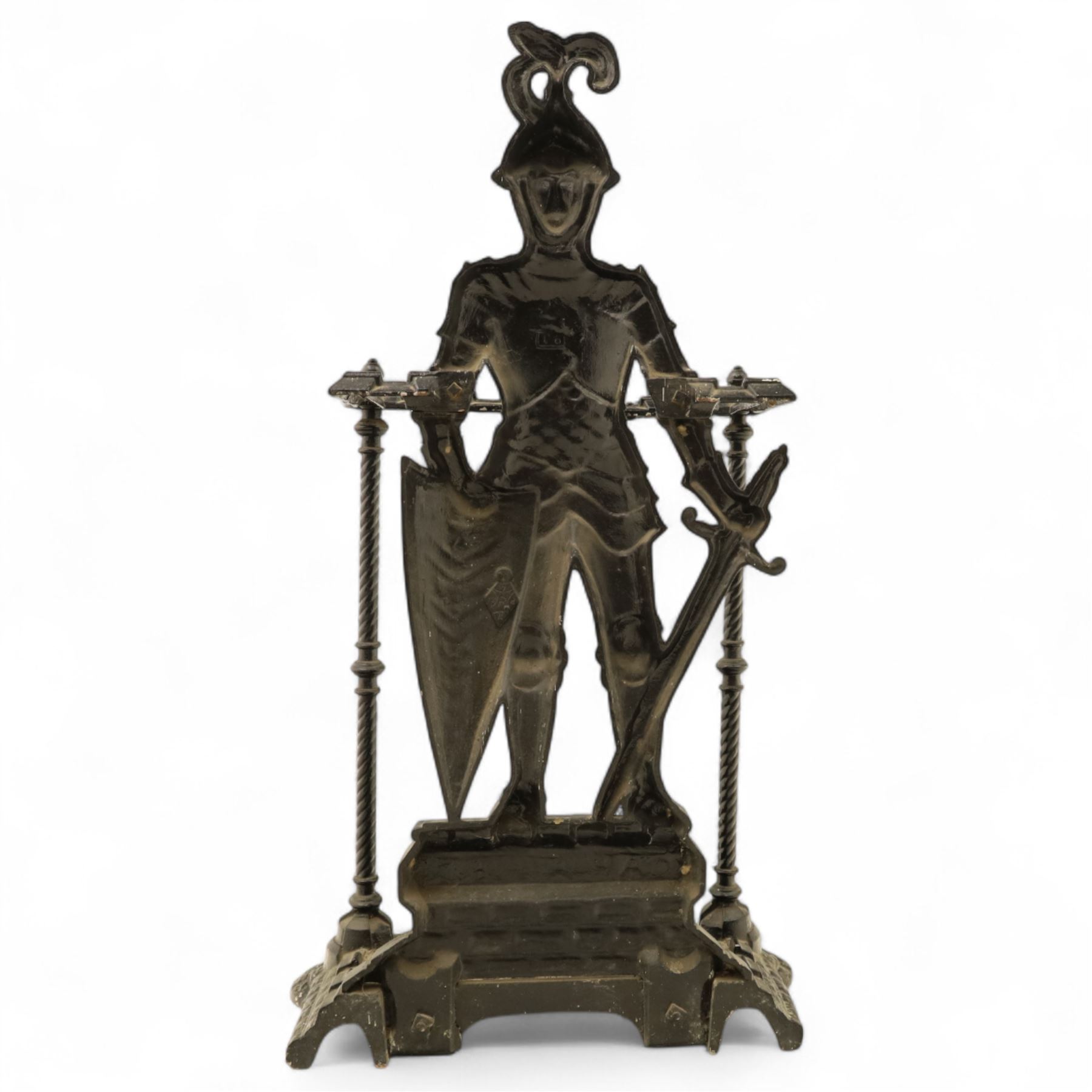 Early 20th century painted cast iron hall stand, formed as a standing armoured figure with red and yellow feathered crest, twin rails and integral drip tray with castellated edge