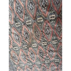 Large Persian Bokhara wool rug, the field decorated with repeating gul motifs in lozenge medallions across a dark ground, enclosed by multiple geometric borders in indigo, ivory and terracotta, from the region of Baluchistan