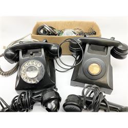 Two vintage black Bakelite telephones, one with a rotary dial and one 'call to exchange', together with three spare Bakelite handsets and additional telephone spare parts. 