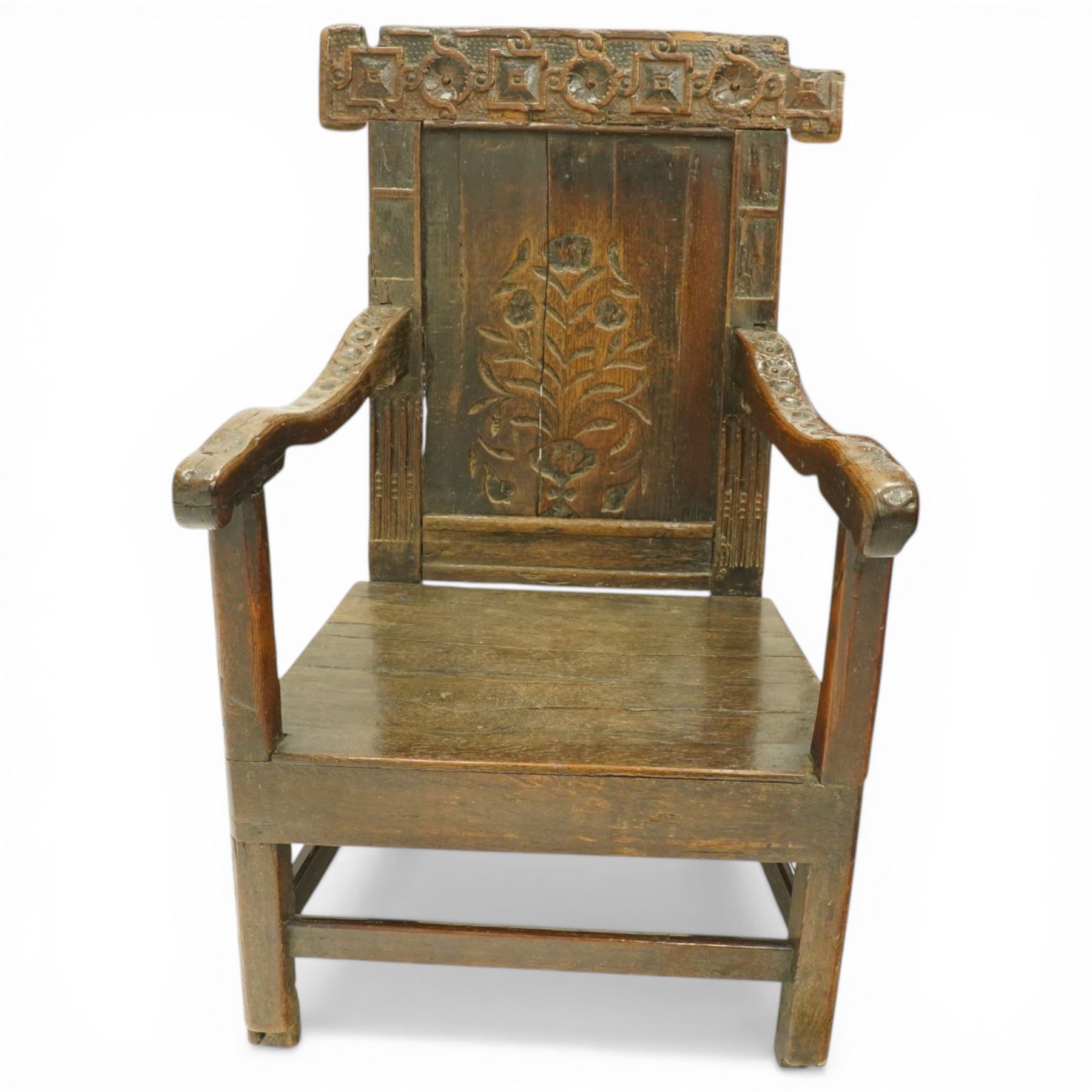 17th century Carolean oak Wainscot chair, the pokerwork cresting rail with carved geometric decoration, over a foliate carved back panel with arcade carved uprights, the arms with repeating guilloche carvings, raised on square chamfered supports united by castors