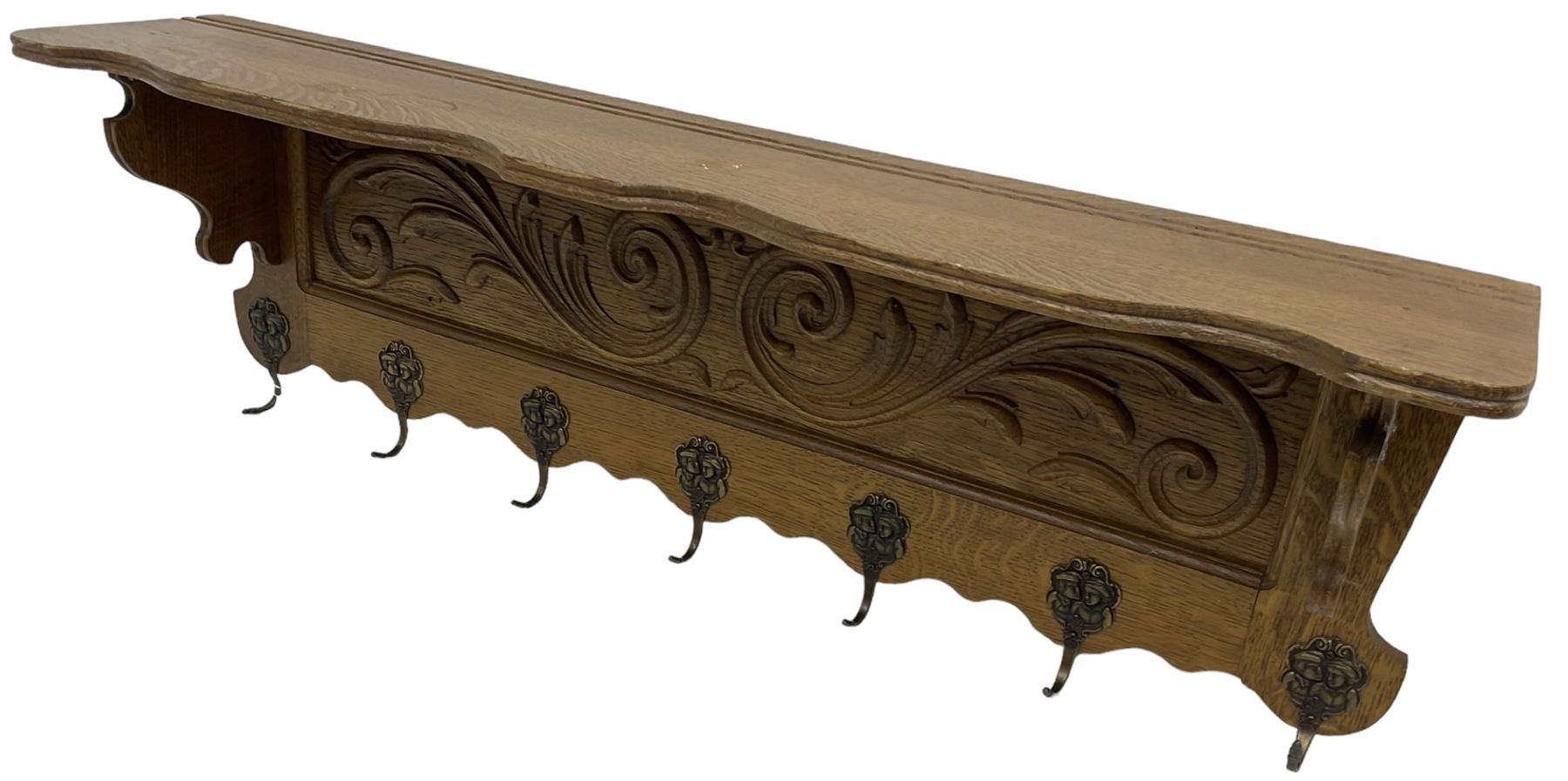 Oak wall hanging coat rack, shape lintel over panelled back carved with foliate S-scrolls, fitted with seven hooks