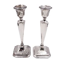Pair of early 20th century silver mounted candlesticks, of tapering fluted form, upon a weighted stepped domed square base with canted corners, hallmarked Henry Williamson Ltd, Birmingham 1915, H26cm