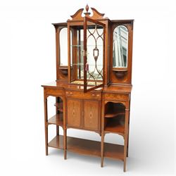 Edwardian Sheraton Revival inlaid mahogany breakfront cabinet, the broken swan neck pediment with central finial inlaid with cartouche and scrolling floral festoons, the central cabinet fitted with astragal-style glazed door with central urn and swag motif, flanked by arched bevelled mirrors over a shelf and gadrooned bracket over paterae inlays, base fitted with marquetry frieze rawer over a panelled cupboard with intricate inlaid scrolling floral designs, flanked by open shelves, raised on square tapering herringbone inlaid supports united by undertier