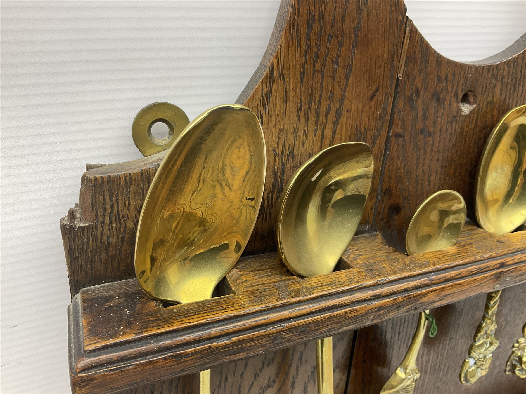 George III oak spoon rack and candle box, the rectangular backplate with shaped  pediment and two six aperture spoon racks, above a candlebox with hinged cover, with various brass spoons and a pair of brass candle snuffers, H56.5cm, W35cm, D14cm 