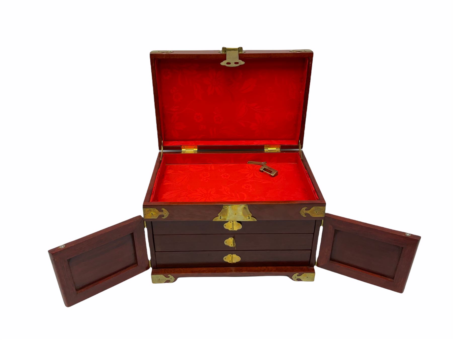 Chinese hardwood jewellery box mounted with engraved brass fixtures, the two exterior doors revealing three drawers below the hinged upper lid, lined with red material decorated with floral sprays, H25cm, W36cm, D23cm