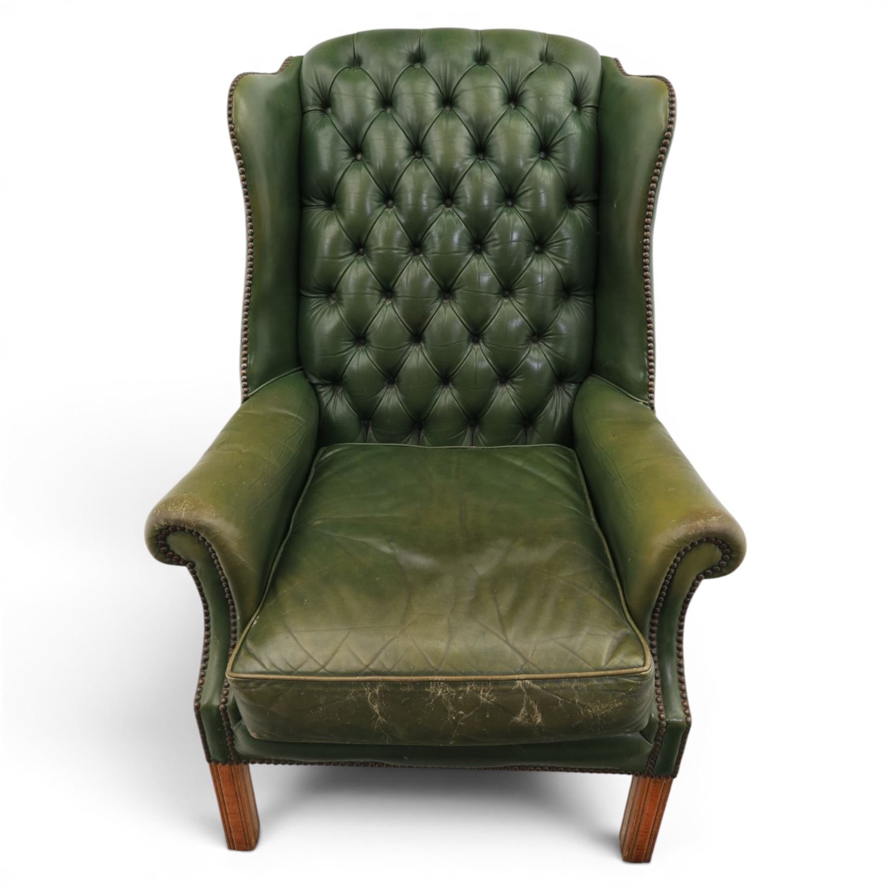 20th century green leather wingback button backed armchair, brass studded trim, with scrolled arms raised on oak supports