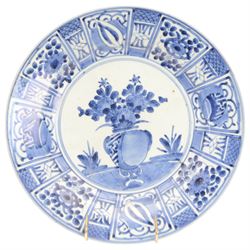 Two Japanese Edo period Ko Imari blue and white porcelain chargers, each decorated in the Kraak style with urns issuing peonies, pine and prunus, within panelled borders containing flowers, tress and precious objects, each approximately D 31.5cm