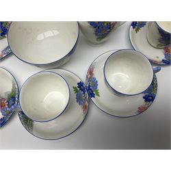 Shelley Strand shaped tea wares, decorated with blue and pink daisies upon a white ground, comprising four teacups, four saucers, three tea plates, milk jug, sugar bowl and cake plate, all with printed green mark beneath and painted pattern no 12216