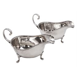 Pair of 1930s silver sauce boats, of typical plain form, each with bead and dart rim and flying scroll handles, upon three pad feet, hallmarked Walker & Hall, Birmingham 1935