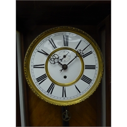  Late 19th century Vienna style walnut wall clock with carved pediment over a glazed door flanked by turned half columns enclosing an enamel dial with Roman numerals and subsidiary seconds dial, single weight driven movement and moulded base with finials H126cm  
