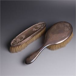 Early 20th Century silver mounted dressing table set, comprising hand mirror, shoe horn and a button hook, each with engraved floral decoration, together with a silver mounted hairbrush and clothes brush, all hallmarked