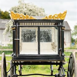 Victorian Glass Hearse

A black painted four wheeled horse drawn glass hearse with extensively glazed coffin compartment, etched glass side and end panels, decorative gilt cresting, gilt column capitals, white painted interior bier deck, metal coffin rails with cross finials, rear glazed access doors, external coachman's box seat for two, wooden spoked wheels the wheel hubs stamped 'The Economic Funeral Co', leaf spring suspension, underbody turntable steering and pole for driving with a pair of horses. The hearse has decorative painted lining throughout and an ornate black and gilt body with curved glass panels to the sides and rear.

Features

• Extensively glazed coffin compartment
• Etched glass side and end panels
• Decorative gilt cresting
• Gilt column capitals
• White painted interior bier deck
• Metal coffin rails with cross finials
• Rear glazed access doors
• External coachman's box seat
• Wooden spoked wheels
• Leaf spring suspension
• Underbody turntable steering
• Pole for driving with a pair of horses
• Decorative painted lining

Dimensions:
Overall length: 406 cm
Body length: 250 cm
Overall width: 190 cm
Body width: 115 cm
Height: 228 cm

Wheel Diameters:
Front wheels: 102 cm
Rear wheels: 133 cm

Seating

Coachman's box seat: 2