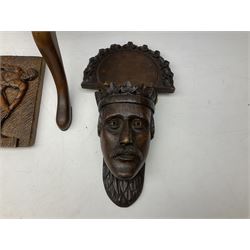 Oak wall bracket, cared in the form of a king with a hinged shelf, together with a wooden plant stand on a carved column and flared legs and a carved wooden plaque 