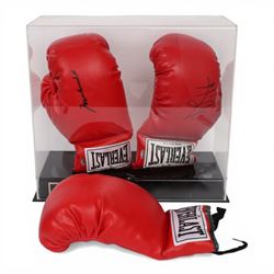 Muhammad Ali and George Foreman signed boxing gloves, two Everlast gloves the left hand glove signed by Ali and right signed by Foreman, both in black marker pen, in Perspex display case with plaque to base displayed with a further unsigned glove, each with Mounted Memories holographic stickers, case H36cm