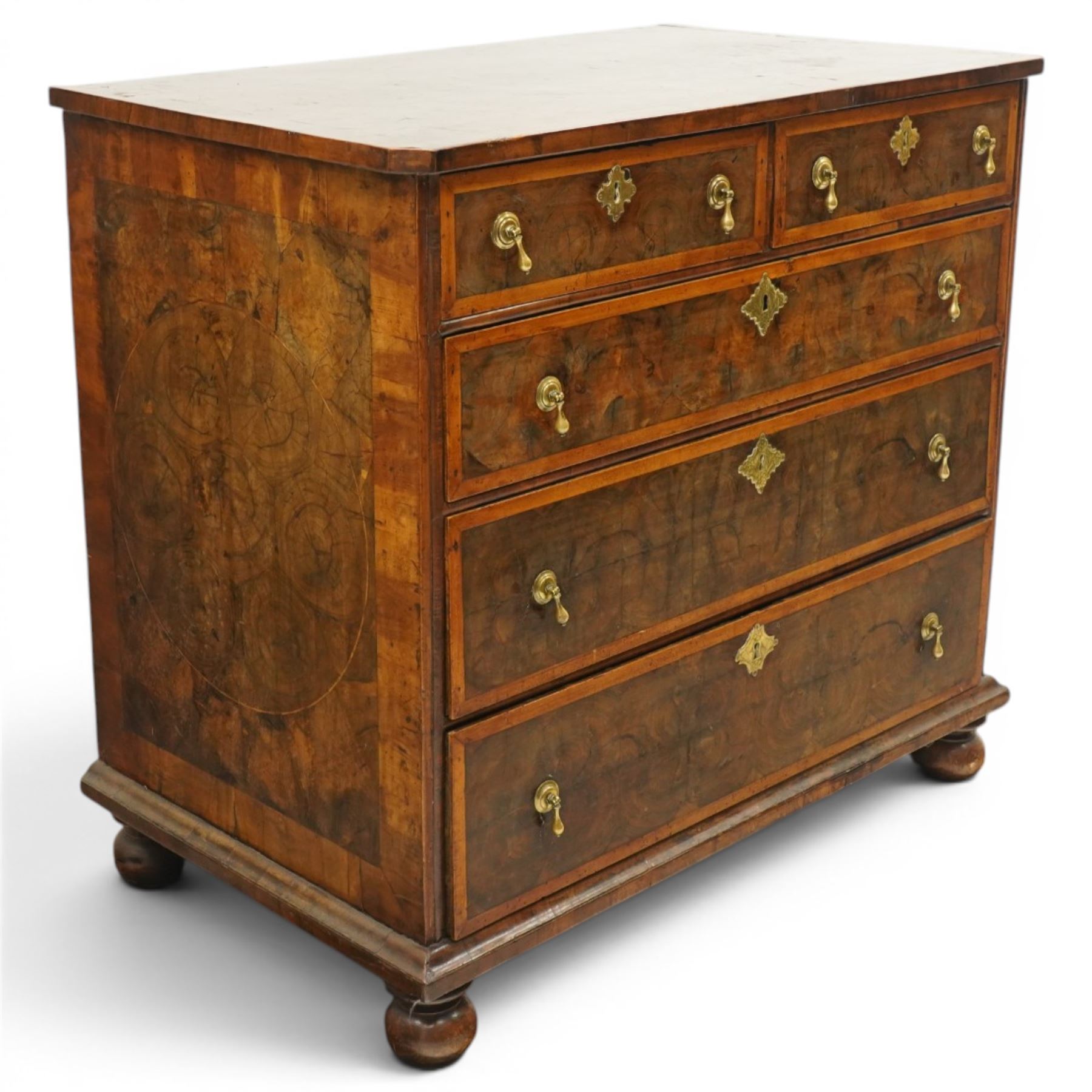 William & Mary period laburnum and walnut oyster-veneered chest, the rectangular top with canted corners and walnut banded edge, profusely decorated with oyster veneer and fruitwood stringing in concentric circles, fitted with two short over three long drawers with fruitwood banding, each fitted with original pressed brass escutcheons and pull handles, lower moulded edge over original bun feet