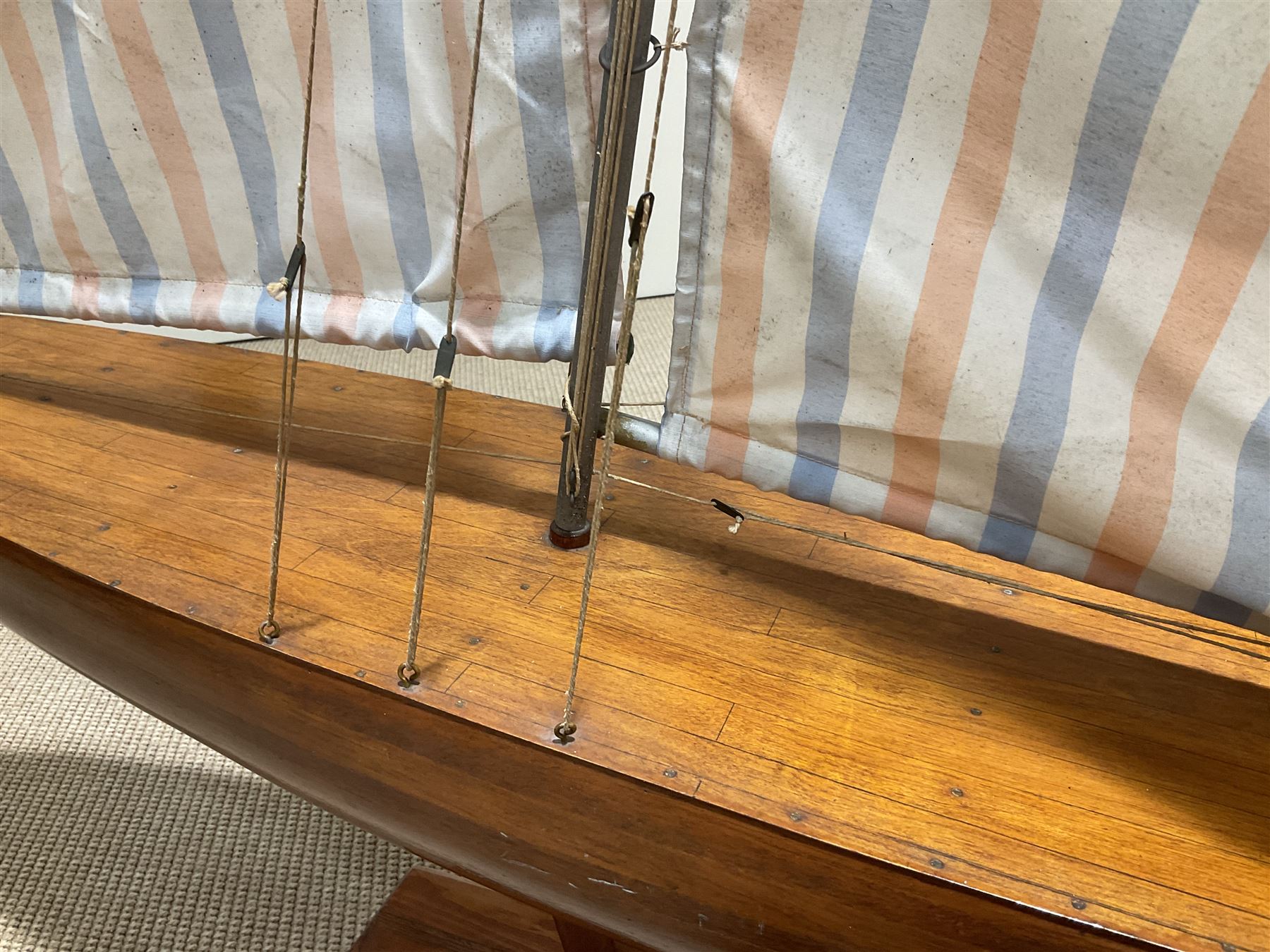 Large pond yacht with simulated planked mahogany deck, mahogany hull, wooden keel and stern fin and tubular aluminium mast with two sails; on wooden stand L131cm H on stand 177cm