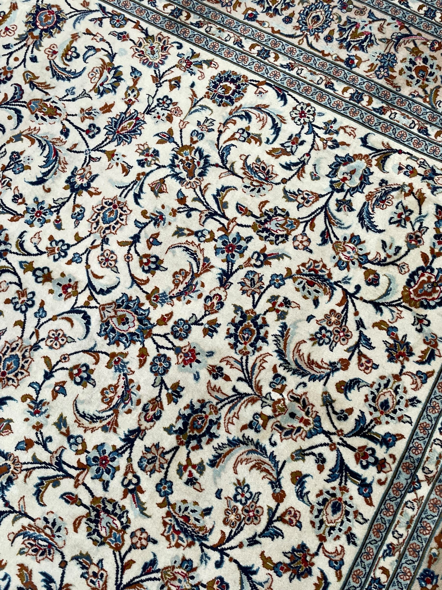 Persian Kashan ivory ground rug, decorated with curled leafy branches and palmettes, the border with scrolling design decorated with further palmettes, within floral pattern guard stripes