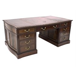 Georgian design serpentine mahogany twin pedestal partners desk, the top inset with tooled leather writing surfaces over six drawers, each pedestal fitted with drawer and one partitioned deep drawer, opposite panelled cupboard enclosing seven plan drawers, with panelled sides, fluted and floral carved decoration, brass drop handles, raised on plinth base, bearing ivorine retailors plaque reading 'JETLEY, LONDON' all drawers oak lined and fitted with HOBBS & CO locks