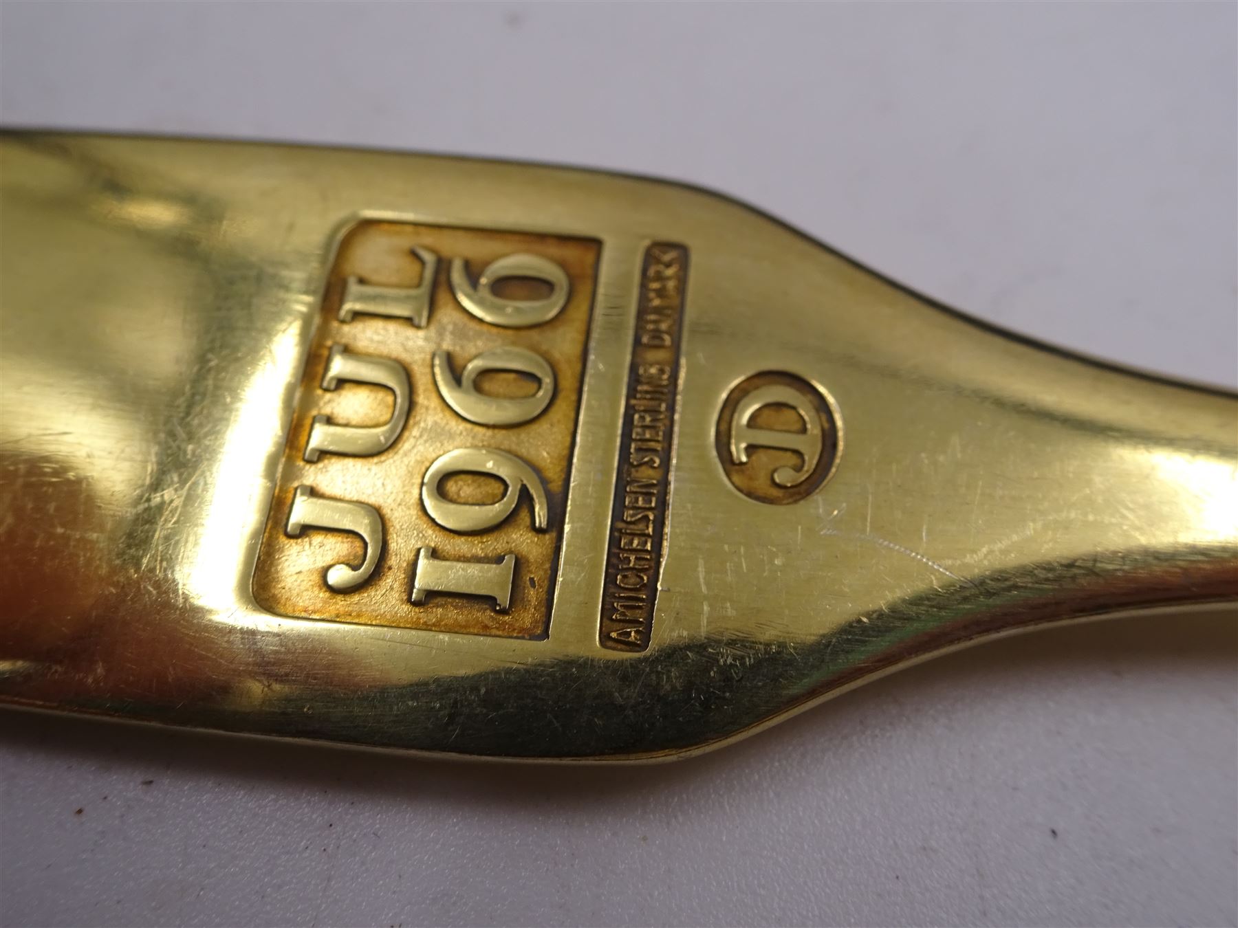 Six Danish silver and silver-gilt year spoons, including four example by Anton Michelsen, each with enamel decoration, including Christmas and other religious designs, dated between 1936 and 1984, each with maker's stamps to underside, together with two silver-gilt examples by Georg Jensen, each with enamel flowers to finials, dated 1975 and 1976, with maker's mark and Sterling Denmark stamped to underside 